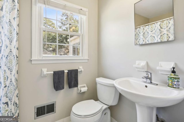 full bathroom featuring toilet, curtained shower, visible vents, and a sink