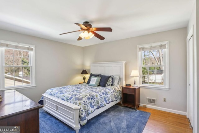 bedroom with ceiling fan, wood finished floors, visible vents, and baseboards