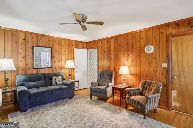 living area featuring crown molding, a ceiling fan, and wood finished floors