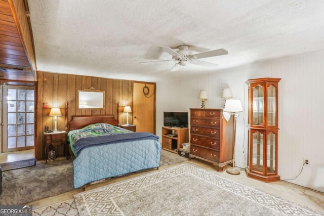 bedroom with a ceiling fan, wood walls, and a textured ceiling