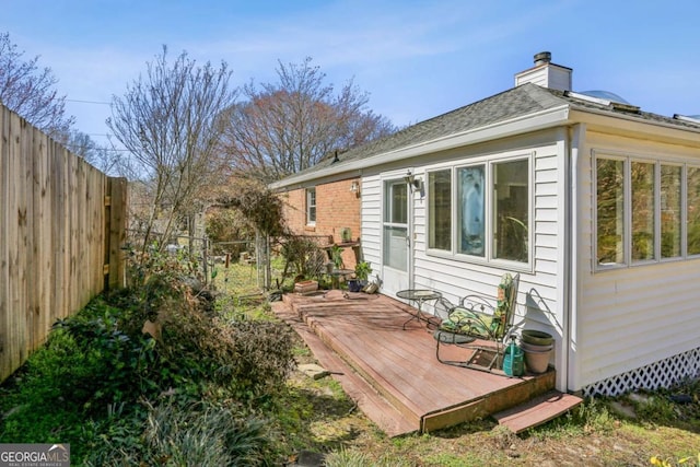 rear view of property with a chimney, a fenced backyard, and a deck