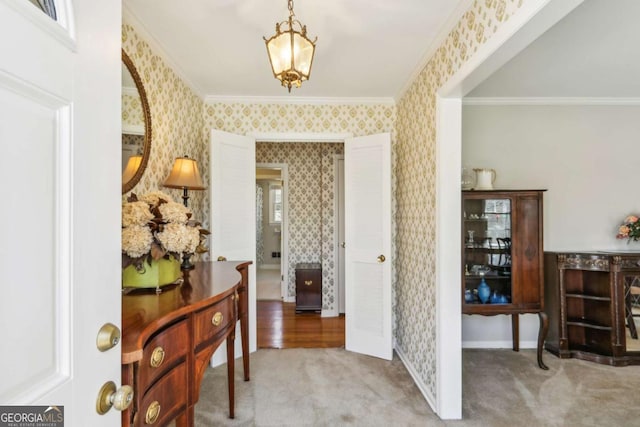 foyer entrance featuring carpet flooring, crown molding, baseboards, and wallpapered walls