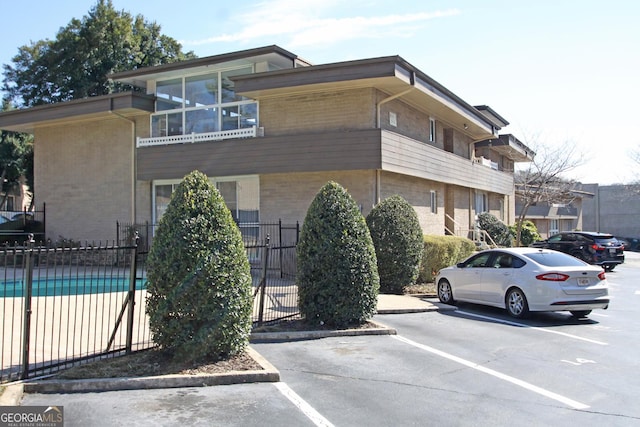 view of property featuring uncovered parking, a fenced in pool, and fence