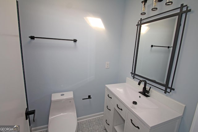 bathroom with vanity, toilet, and baseboards