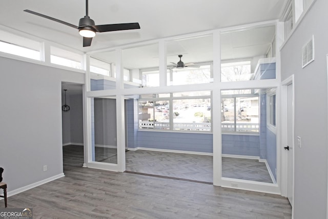 unfurnished sunroom featuring visible vents and ceiling fan