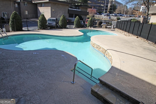 pool with a patio area and fence