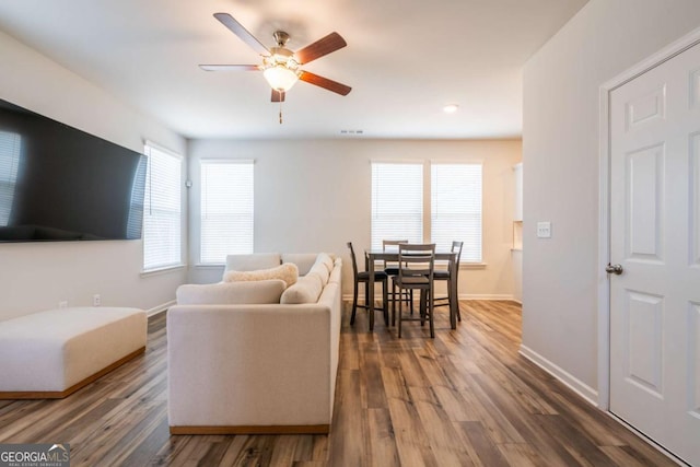 living room featuring ceiling fan, baseboards, and wood finished floors