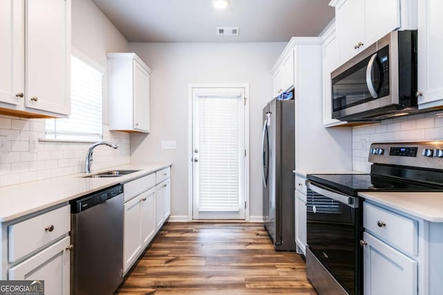 kitchen featuring light countertops, appliances with stainless steel finishes, white cabinetry, a sink, and wood finished floors