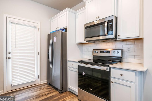 kitchen featuring light countertops, backsplash, light wood-style flooring, appliances with stainless steel finishes, and white cabinetry