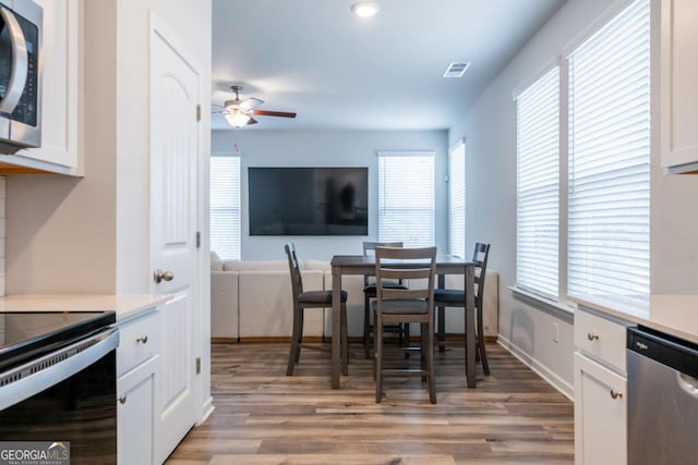 dining area featuring light wood-style floors, visible vents, and a ceiling fan