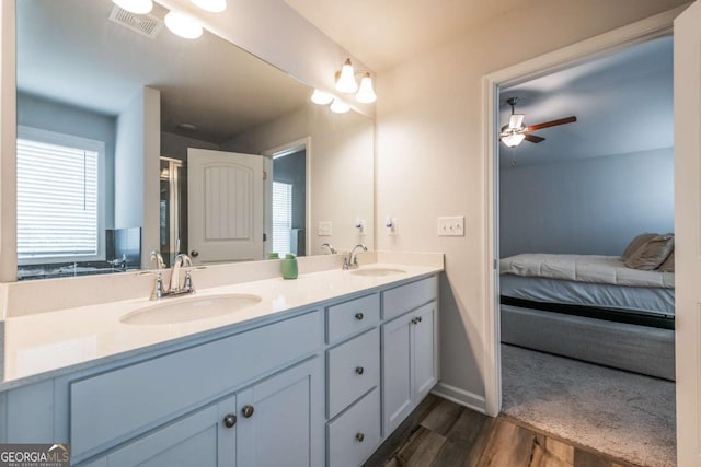 ensuite bathroom with double vanity, a ceiling fan, visible vents, and a sink