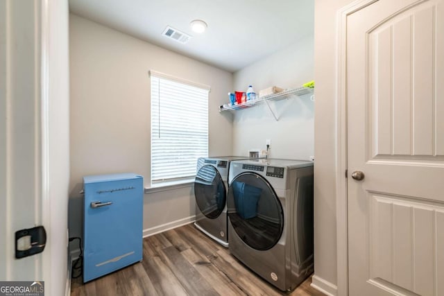 washroom with washer and clothes dryer, visible vents, wood finished floors, laundry area, and baseboards