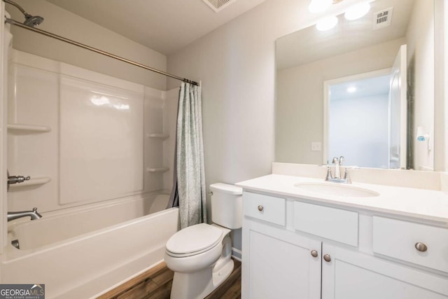 full bathroom with visible vents, toilet, wood finished floors, shower / bath combination with curtain, and vanity