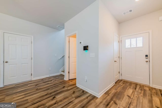 foyer with visible vents, stairway, and wood finished floors