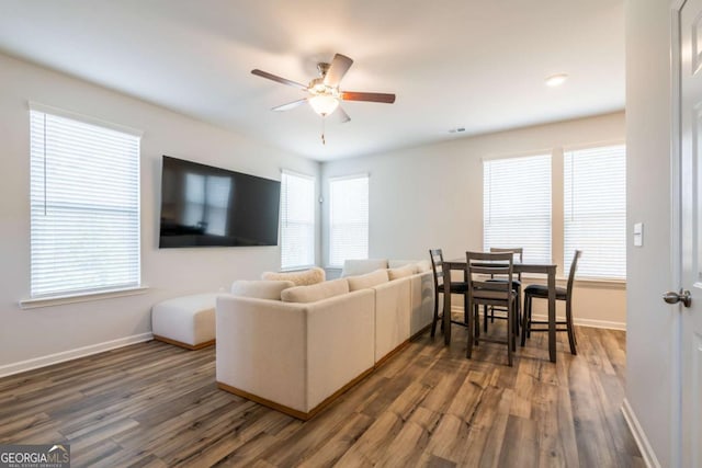 living room featuring visible vents, ceiling fan, baseboards, and wood finished floors