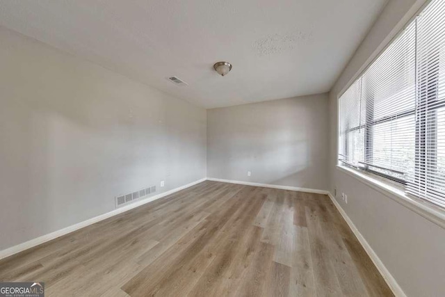 empty room with visible vents, baseboards, and wood finished floors