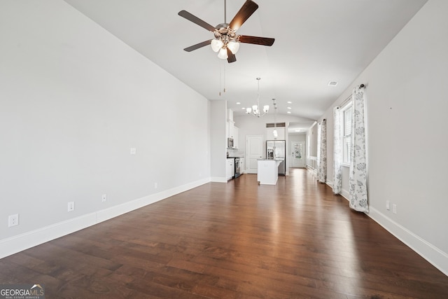 unfurnished living room with visible vents, lofted ceiling, ceiling fan with notable chandelier, dark wood-style floors, and baseboards