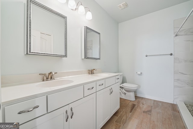 bathroom with double vanity, toilet, wood finished floors, and a sink