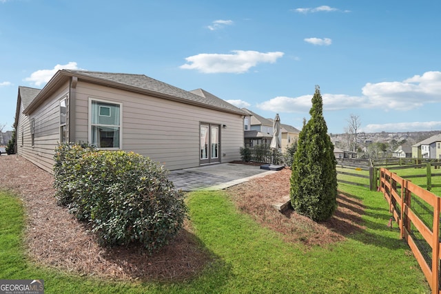 rear view of house featuring fence, a lawn, and a patio area