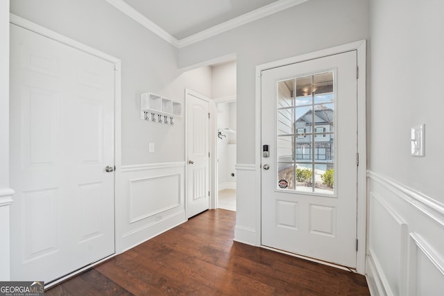 foyer featuring crown molding, a decorative wall, dark wood-type flooring, and wainscoting