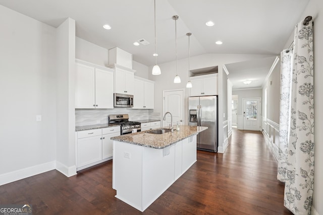 kitchen featuring a breakfast bar, a center island with sink, a sink, stainless steel appliances, and light stone countertops