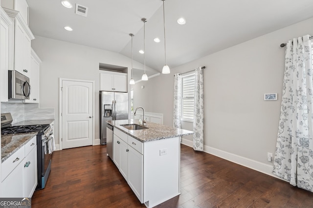 kitchen with dark wood-type flooring, light stone countertops, a center island with sink, appliances with stainless steel finishes, and a sink