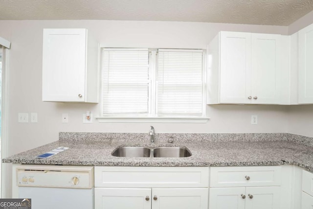 kitchen featuring white cabinets, light stone countertops, white dishwasher, a textured ceiling, and a sink