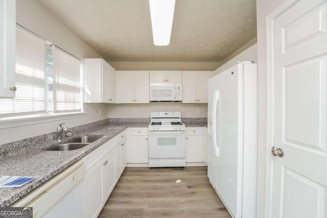 kitchen featuring white appliances, white cabinetry, and a sink