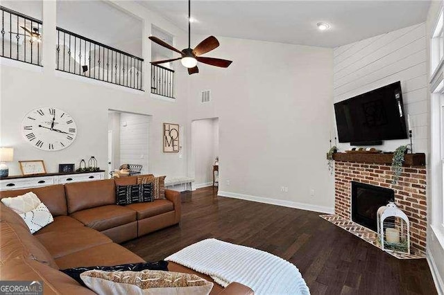 living area with baseboards, visible vents, a ceiling fan, wood finished floors, and a fireplace