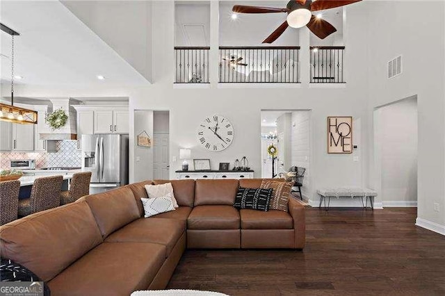 living area with visible vents, dark wood finished floors, baseboards, and ceiling fan