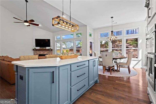 kitchen featuring open floor plan, light countertops, dark wood finished floors, and decorative light fixtures