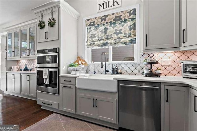 kitchen featuring a sink, gray cabinets, stainless steel appliances, light countertops, and backsplash