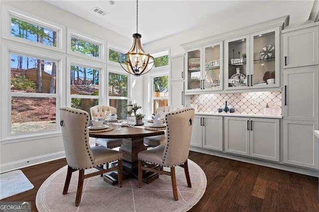 dining area featuring dark wood-style flooring, visible vents, baseboards, and an inviting chandelier