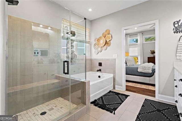 ensuite bathroom featuring baseboards, ensuite bath, tile patterned floors, a shower stall, and a bath