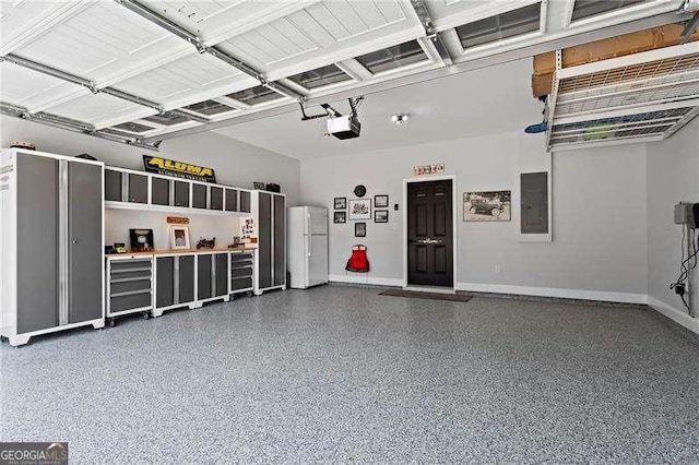 garage with electric panel, baseboards, a garage door opener, and freestanding refrigerator