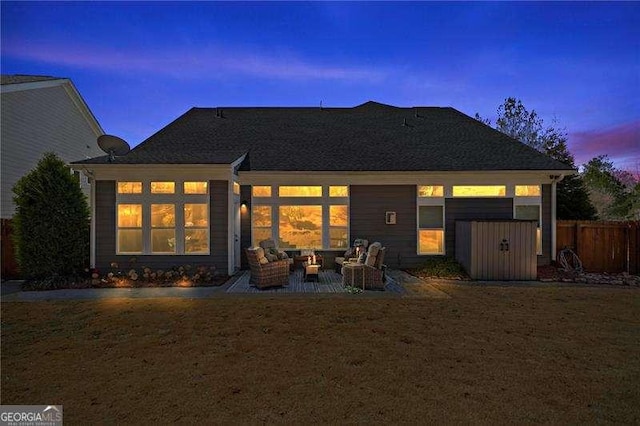 back of property at dusk with a yard and a patio area