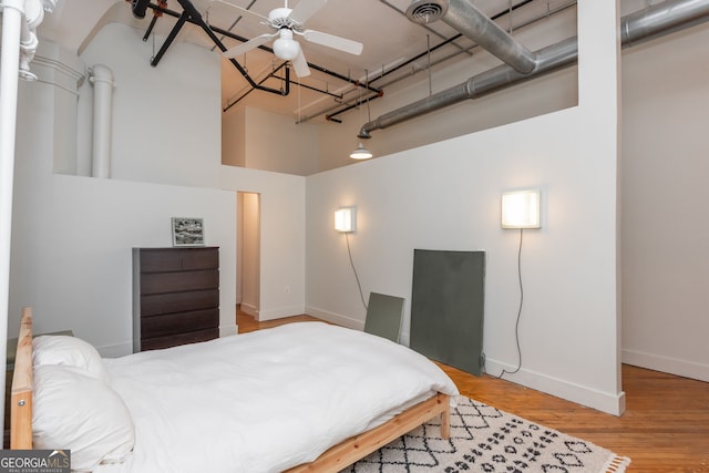 bedroom featuring visible vents, baseboards, a high ceiling, and wood finished floors