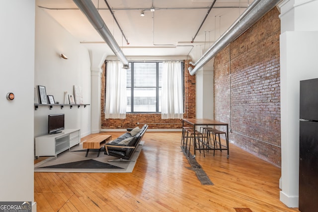 interior space with hardwood / wood-style floors, brick wall, and a towering ceiling