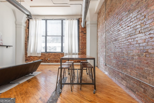 dining area featuring hardwood / wood-style floors and brick wall