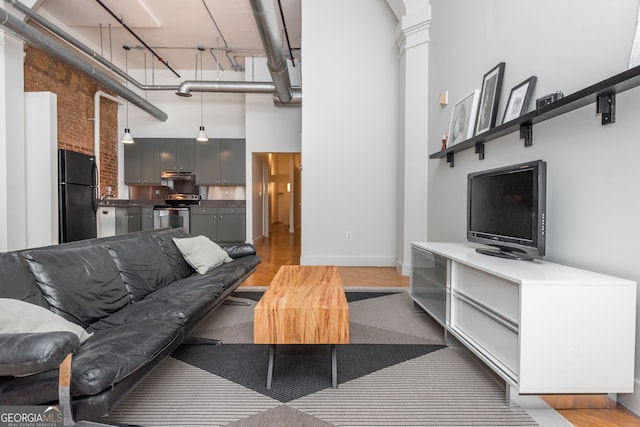 living room featuring light wood finished floors, a high ceiling, and baseboards