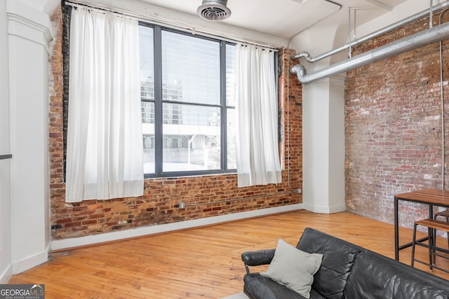 sitting room featuring visible vents, brick wall, baseboards, and hardwood / wood-style floors