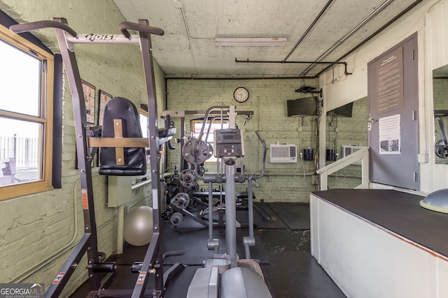 workout area with brick wall and a wall mounted AC