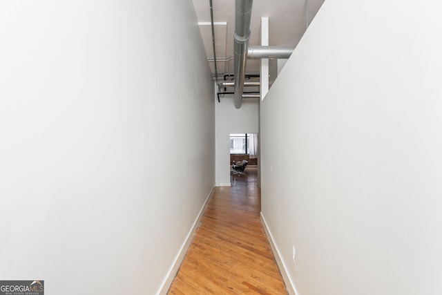 corridor featuring light wood-type flooring and baseboards