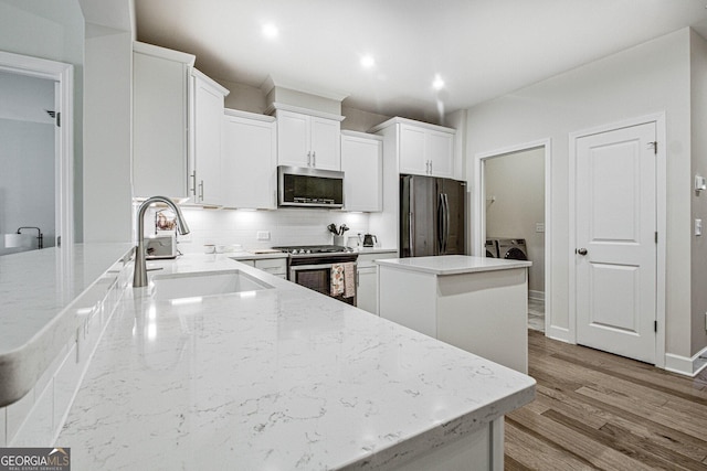 kitchen with a center island, a sink, light stone countertops, stainless steel appliances, and backsplash