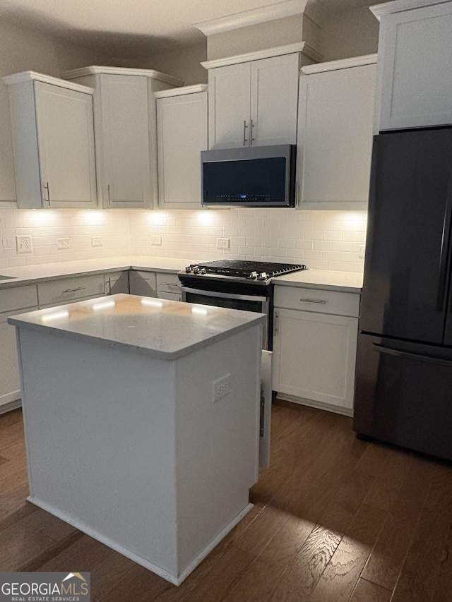 kitchen featuring stainless steel appliances, a center island, dark wood finished floors, and decorative backsplash