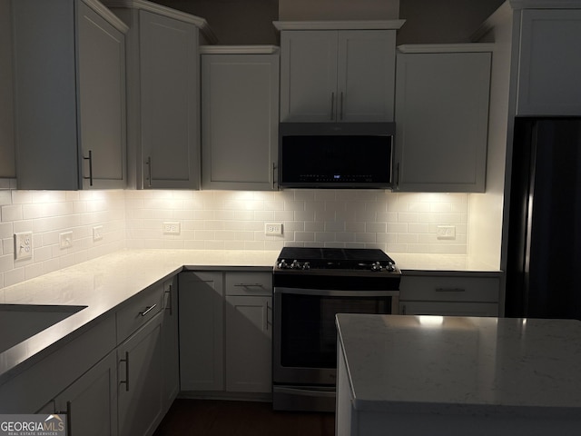 kitchen featuring stainless steel range with gas cooktop, light stone counters, and backsplash