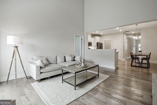 living room with baseboards, a chandelier, wood finished floors, and recessed lighting