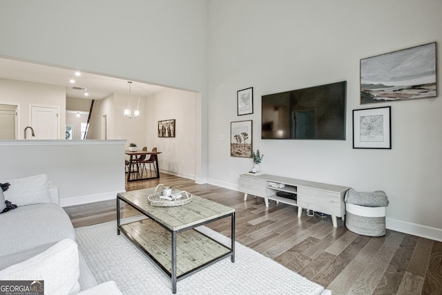 living area with recessed lighting, visible vents, wood finished floors, a chandelier, and baseboards