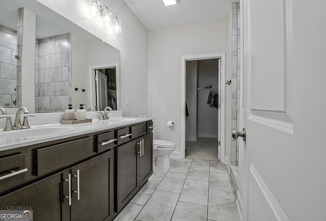 full bath with double vanity, a spacious closet, a sink, and tiled shower