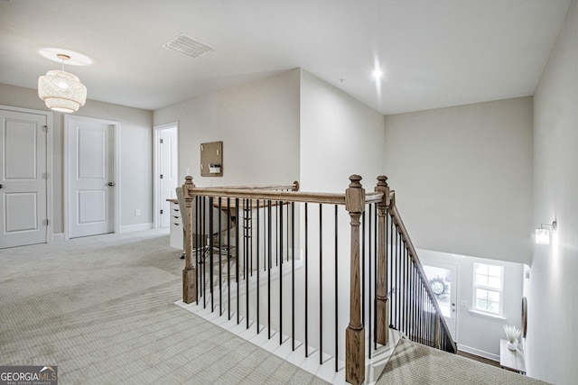 hallway featuring visible vents, carpet, an upstairs landing, and baseboards